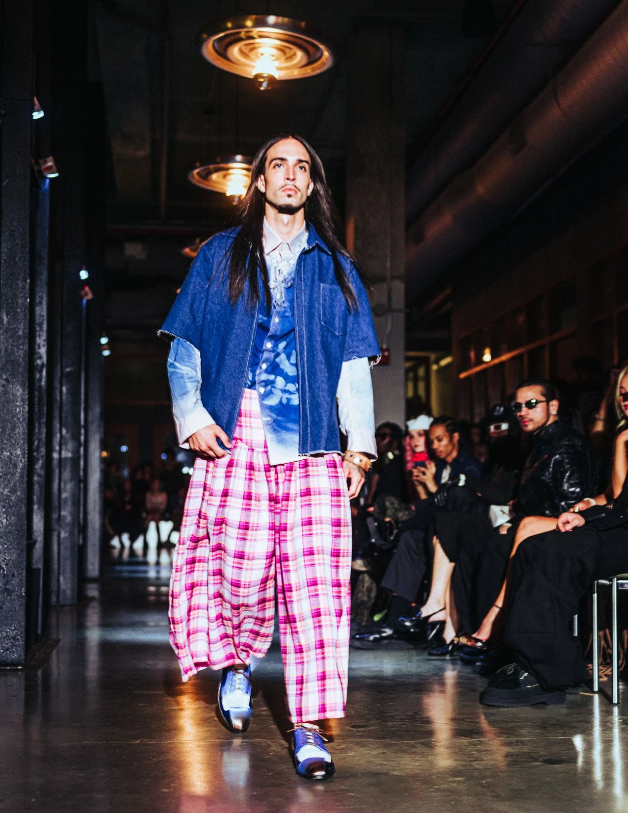 Model in a blue blazer and pink plaid trousers walking toward the camera.