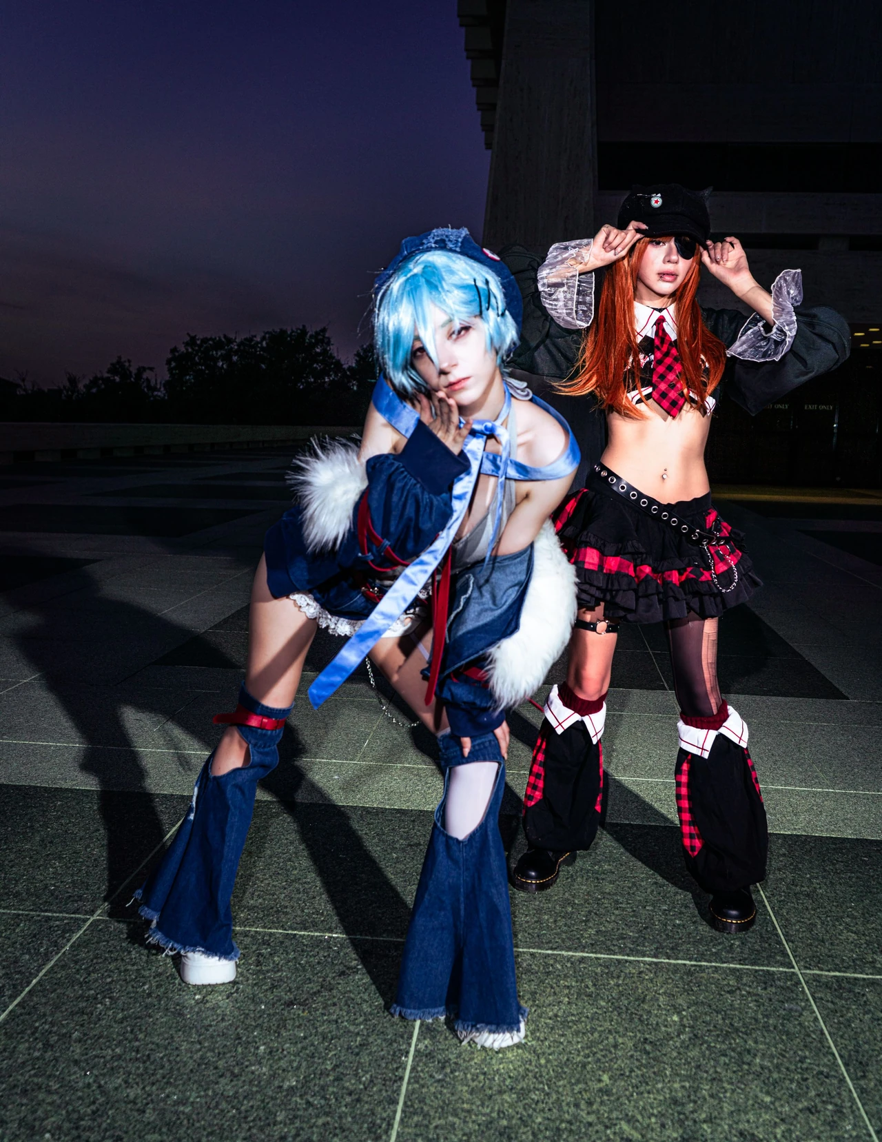 Rei and Asuka cosplay posing one behind the other beneath a dark blue evening sky.