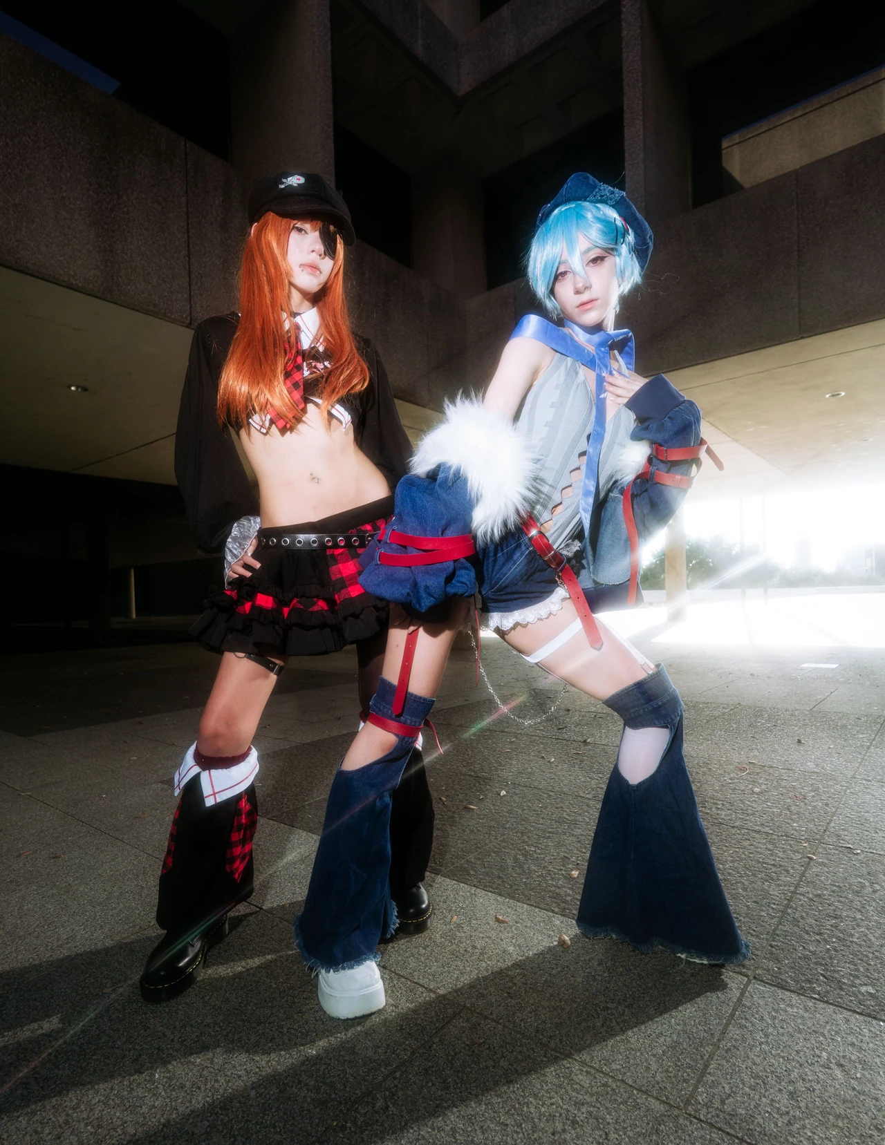 Asuka and Rei cosplay in red plaid and blue outfits standing beneath a concrete overhang.