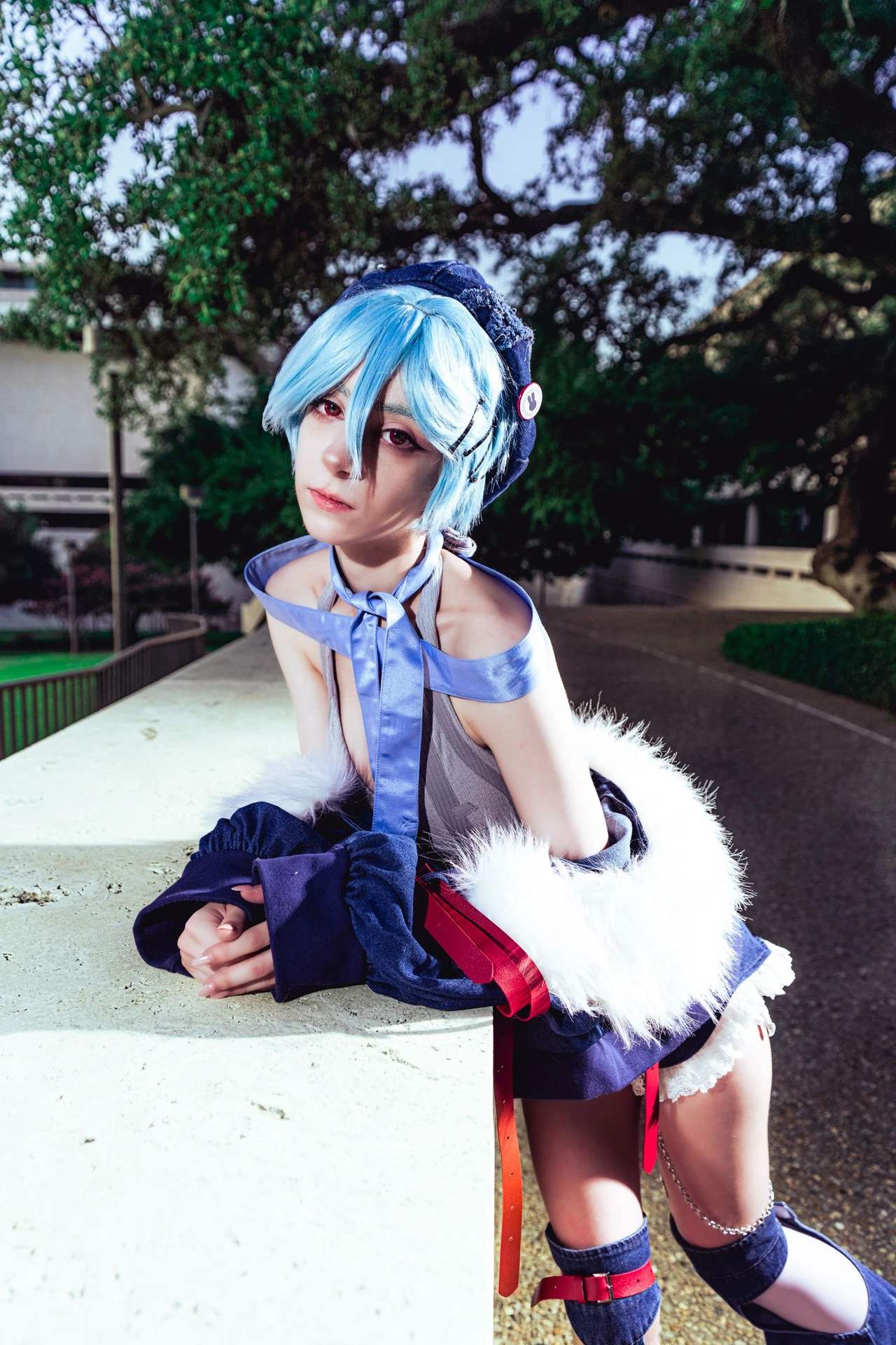 Close portrait of blue-haired Rei cosplay leaning on a pale concrete ledge.