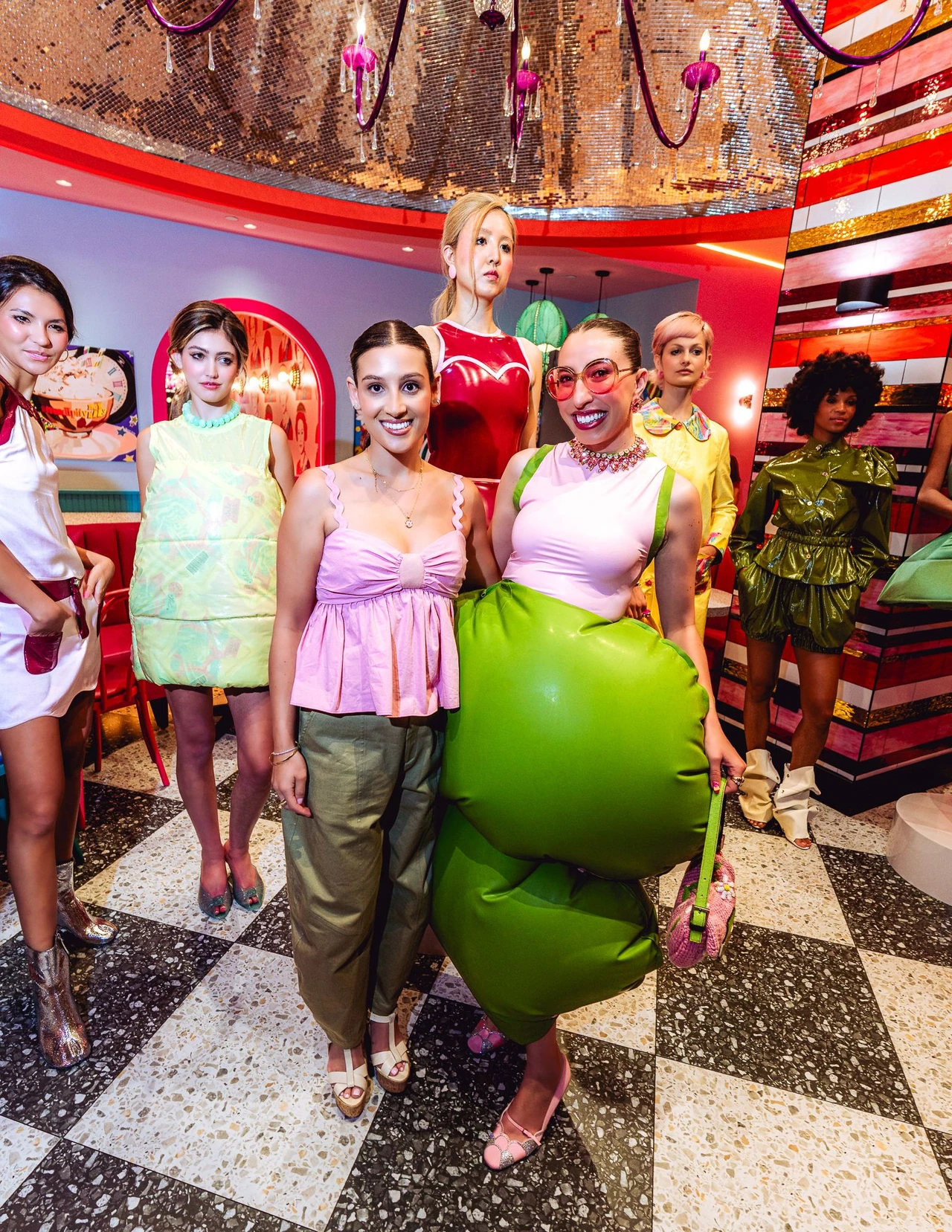 Group of T’ABBE models gathered around a large green inflated garment.