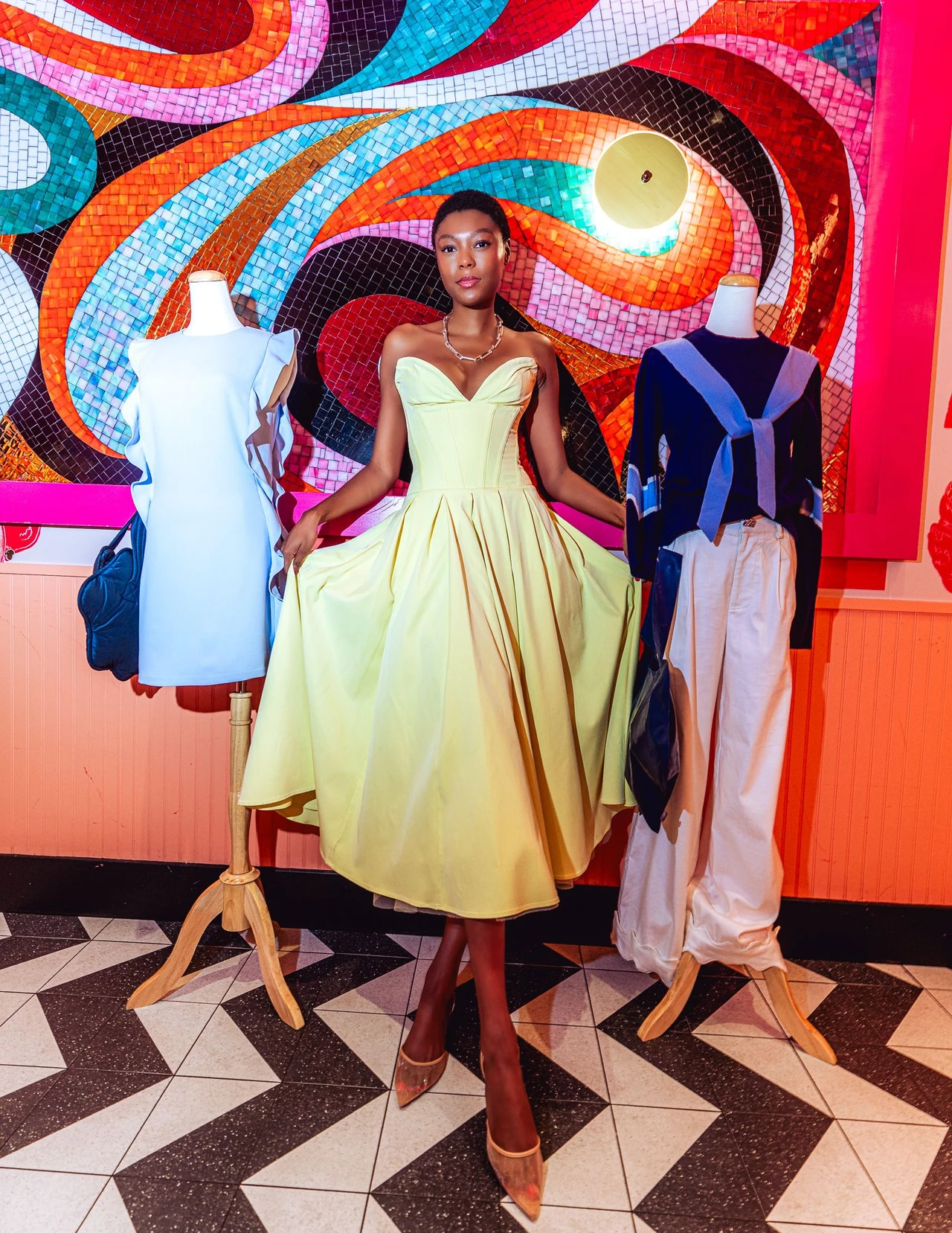 Model in a pale yellow dress photographed beside a colorful mosaic butterfly.
